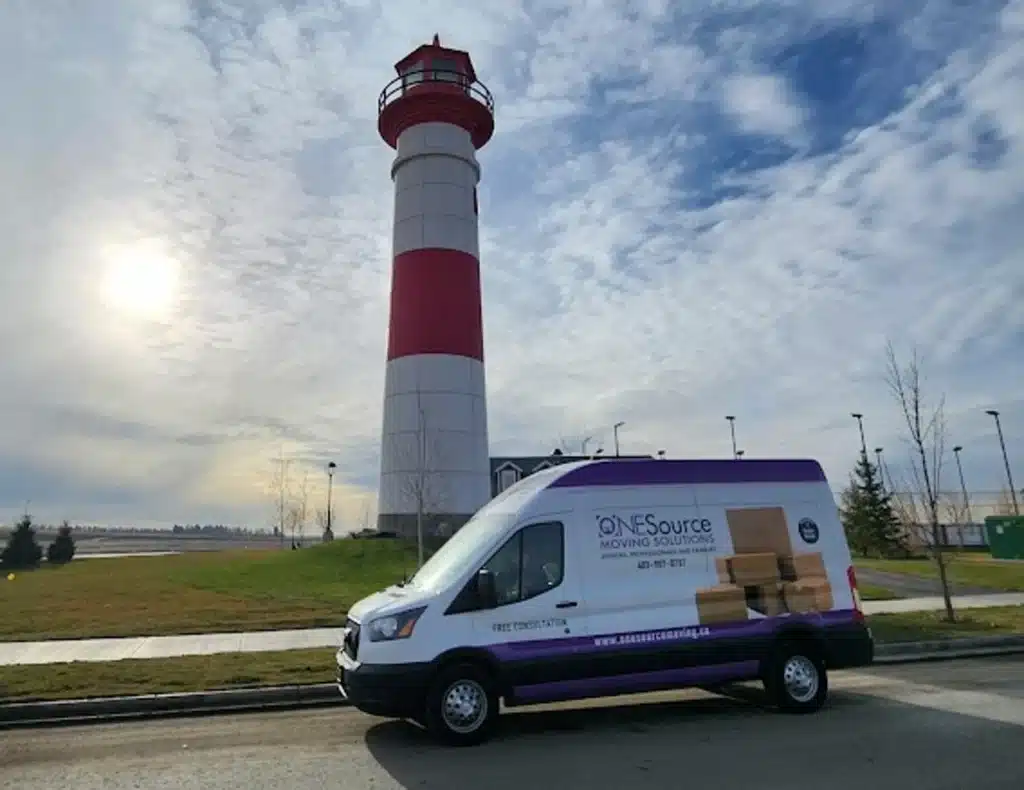 ONESource Moving Solutions van parked beside the Clearwater Chestermere lighthouse, representing senior moving and downsizing services in Chestermere.
